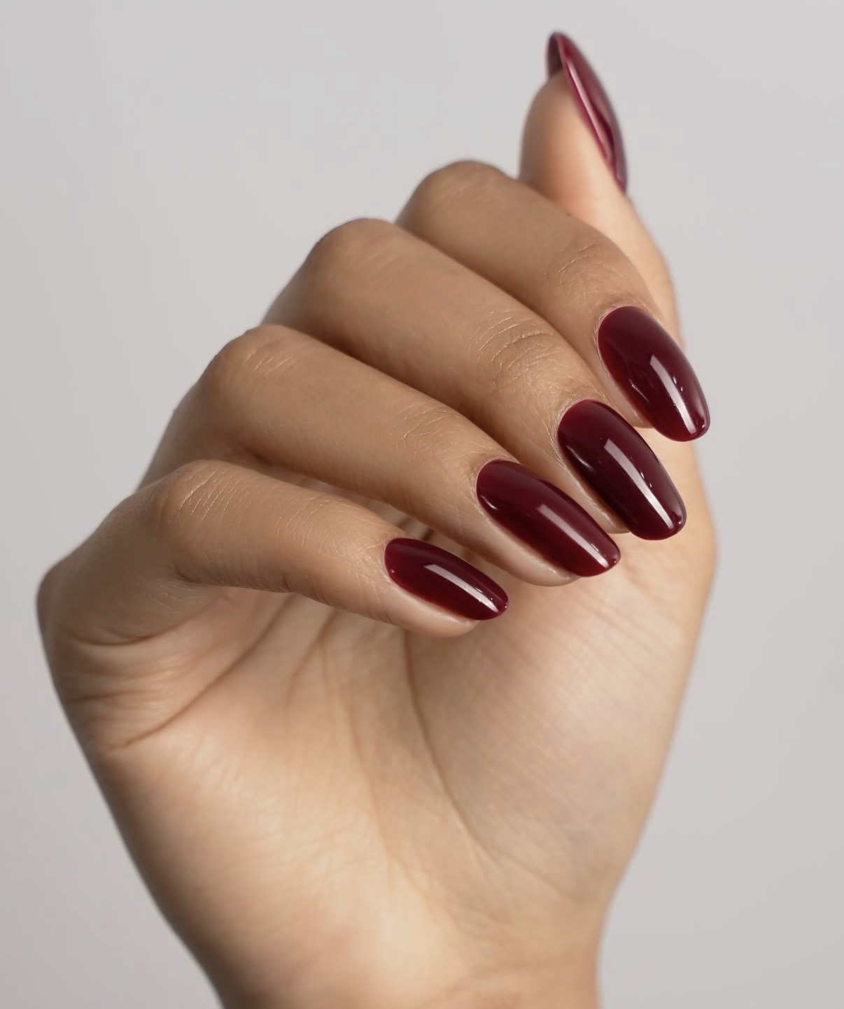 Main aux ongles amande bordeaux brillants
