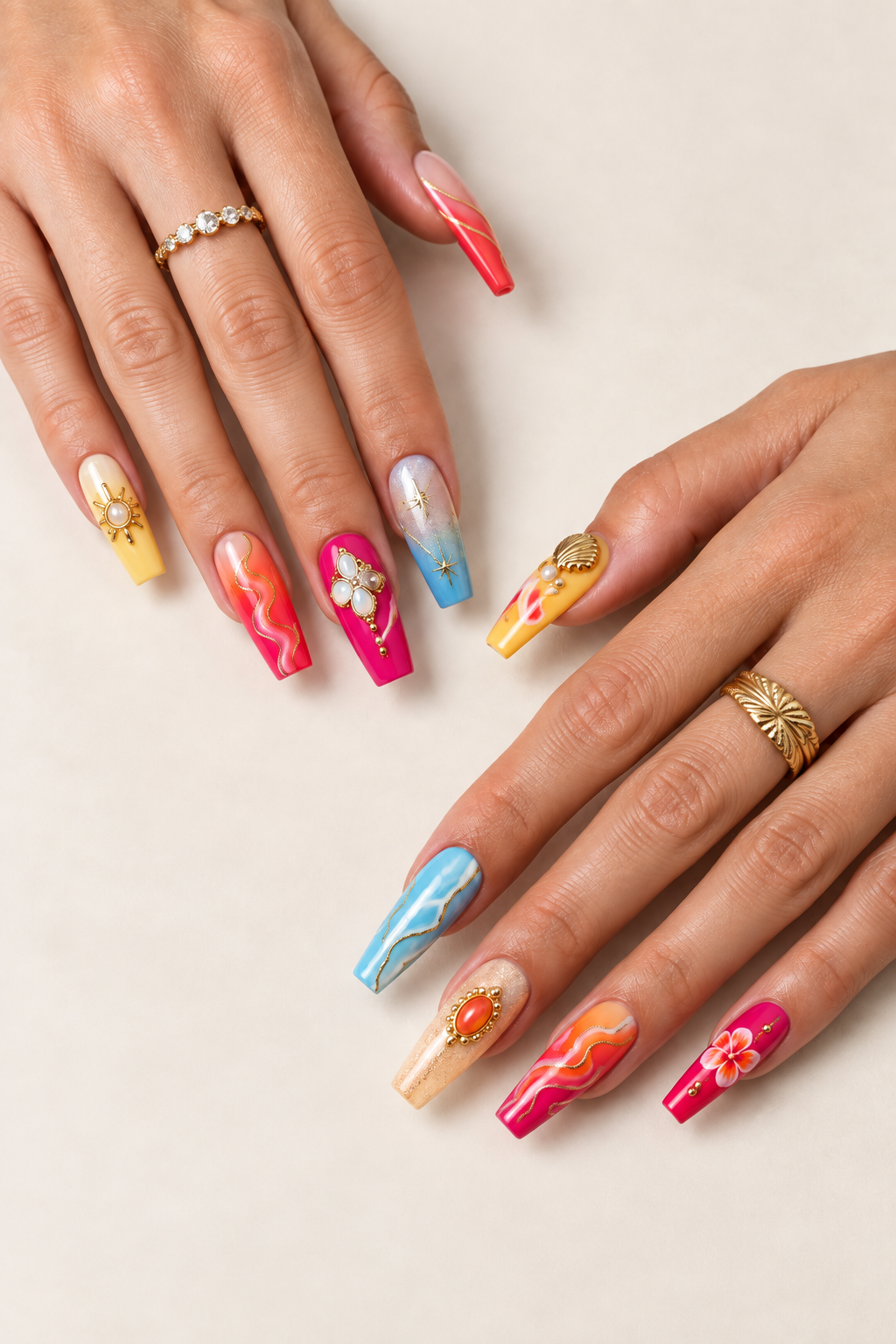 Deux mains aux ongles longs colorés ornés de détails dorés, de fleurs et de coquillages